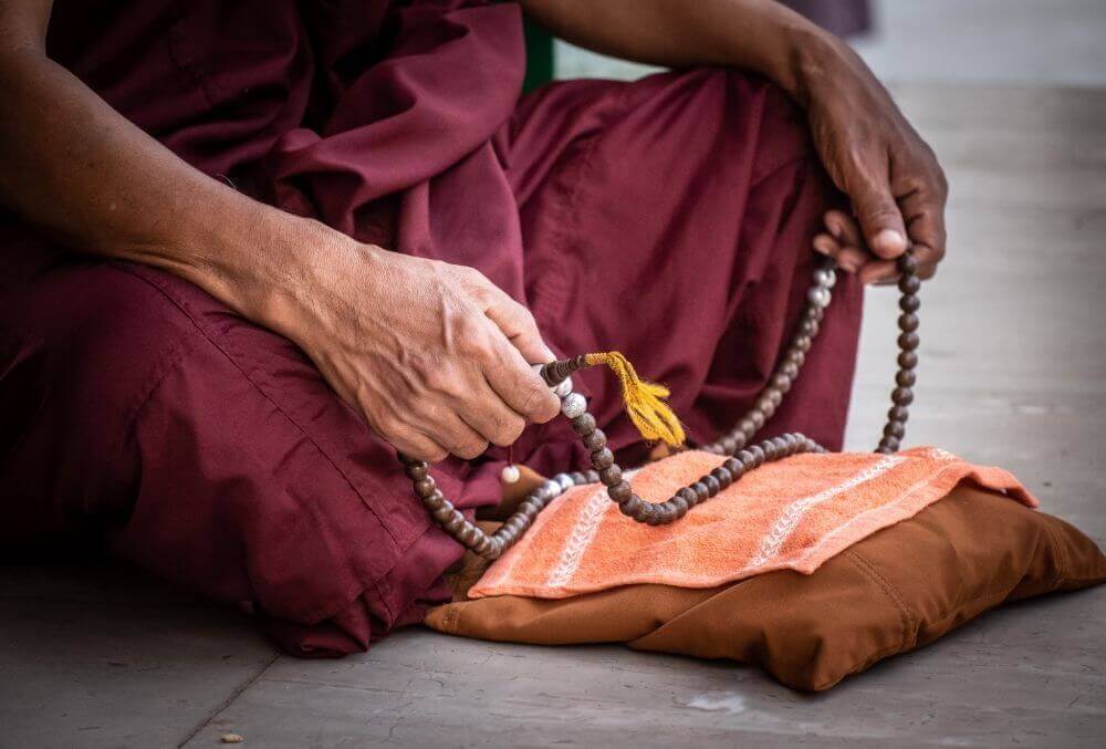 Monk meditating holding Buddah beads